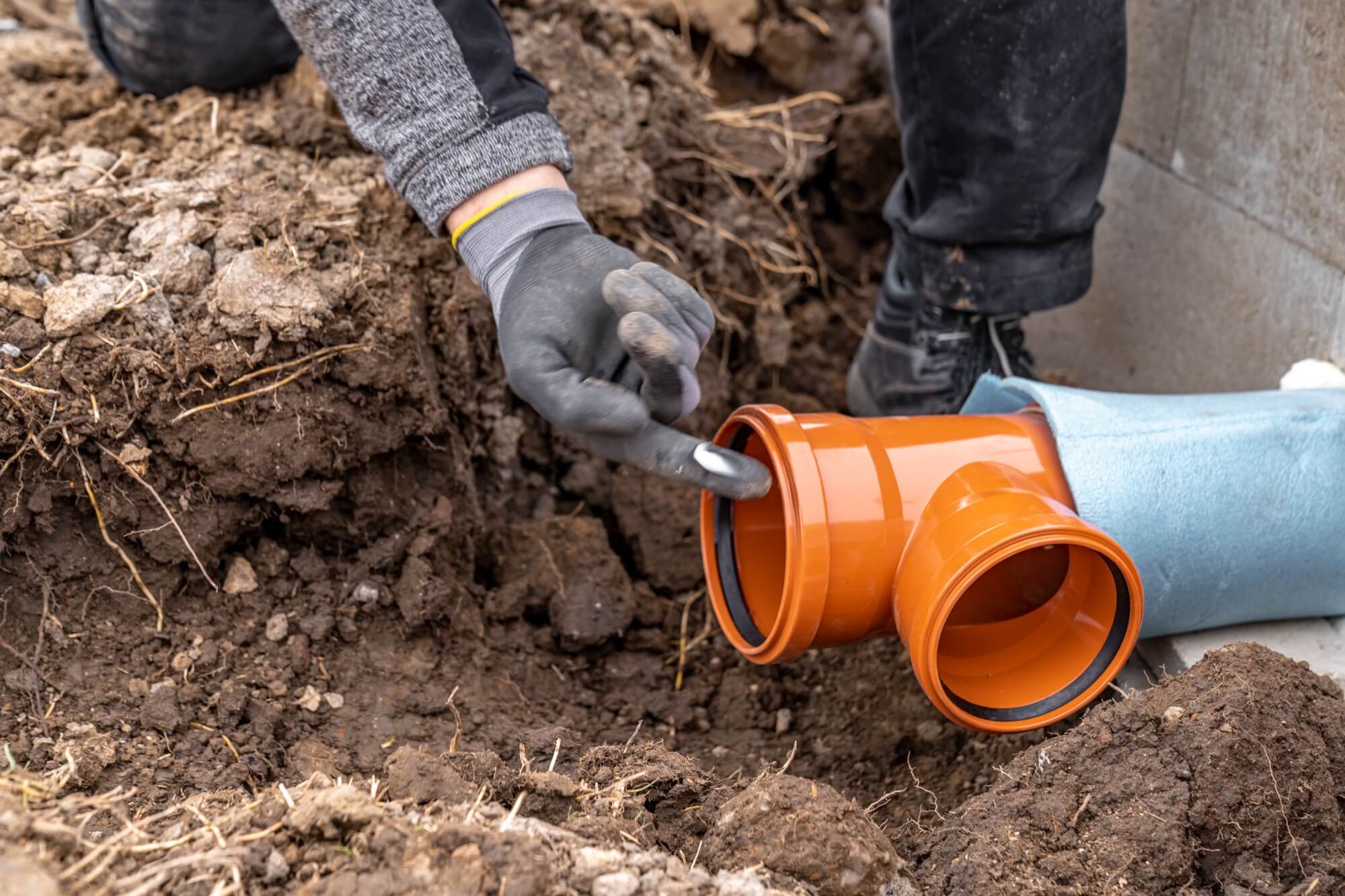 A worker installing an orange pipe as part of a drainage system in .